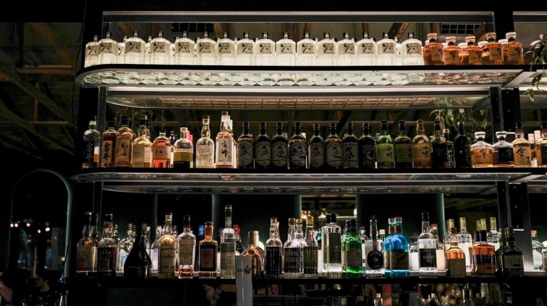 Sake bottles on bar shelf - Japonity